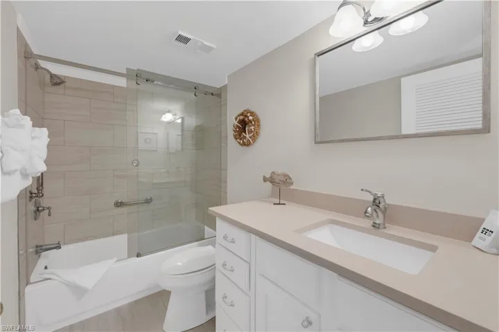 Full bathroom with enclosed tub / shower combo and vanity