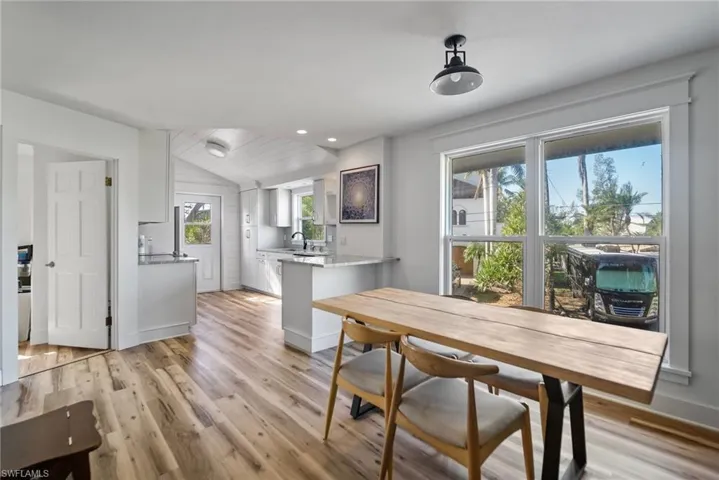 Dining area featuring light wood-type flooring, sink, a wealth of natural light, and vaulted ceiling