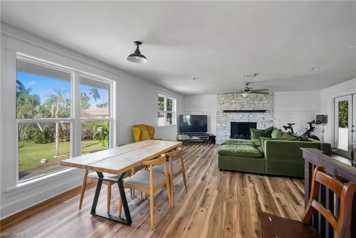 Dining area featuring light wood-type flooring, a stone fireplace, and ceiling fan