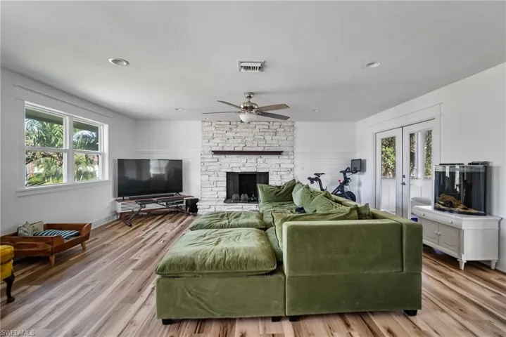 Living room featuring ceiling fan, a fireplace, a wealth of natural light, and light hardwood / wood-style flooring