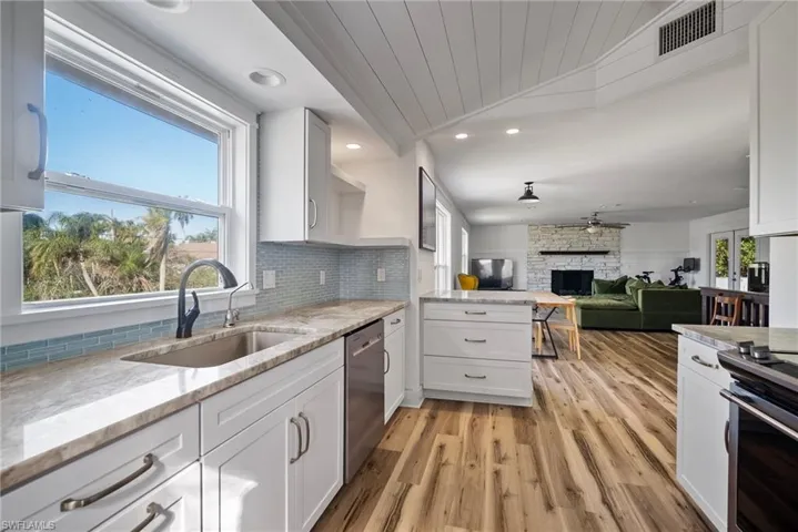 Kitchen featuring sink, appliances with stainless steel finishes, a fireplace, white cabinets, and light wood-type flooring
