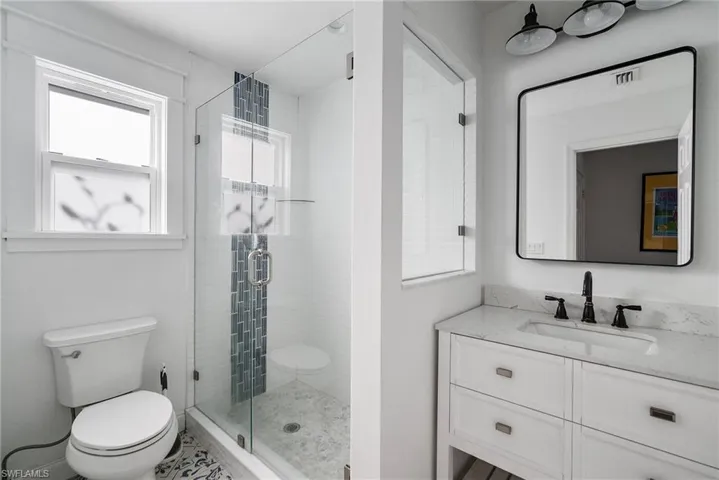 Bathroom featuring vanity, toilet, and a shower with door