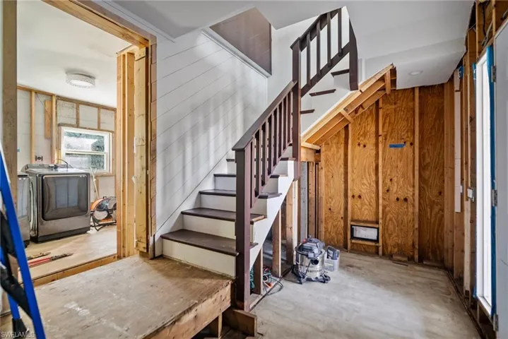 Stairs with washer and dryer, concrete flooring, and wood walls