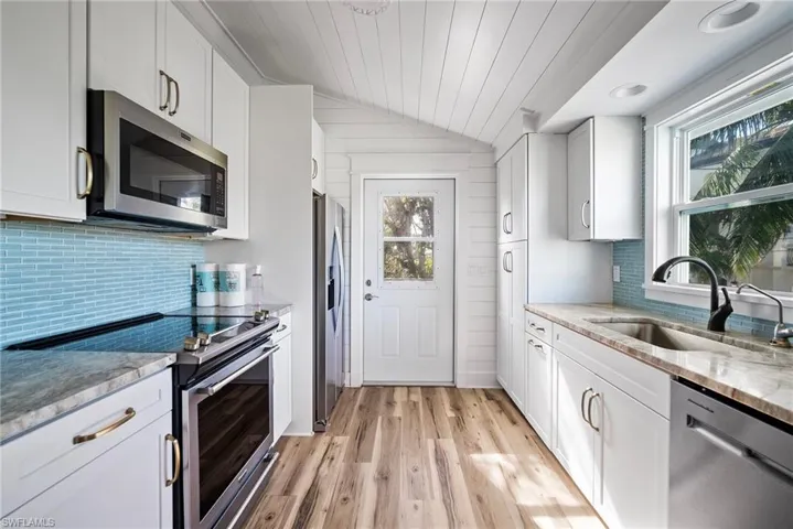 Kitchen with stainless steel appliances, white cabinetry, and a healthy amount of sunlight