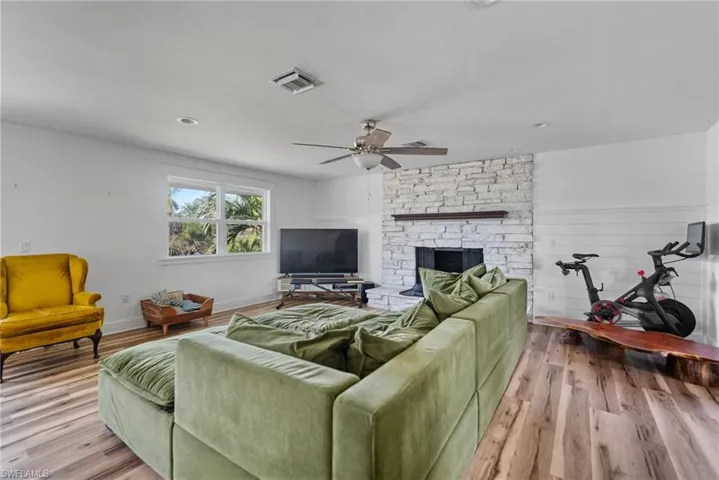 Living room with a fireplace, ceiling fan, and light hardwood / wood-style flooring