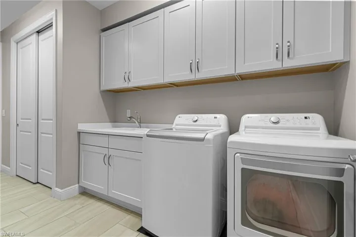 Washroom featuring cabinets, light wood-type flooring, separate washer and dryer, and sink