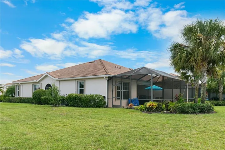 Back of property featuring a lanai and a lawn