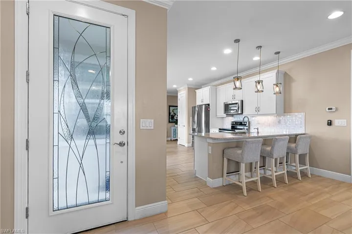 Kitchen featuring white cabinets, pendant lighting, kitchen peninsula, appliances with stainless steel finishes, and a breakfast bar area