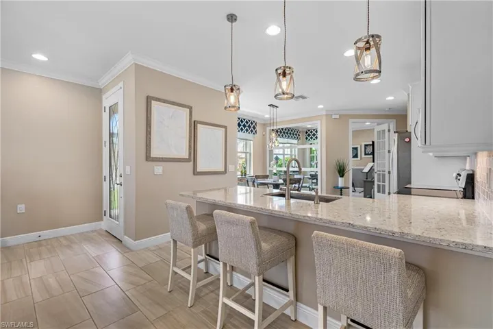 Kitchen with hanging light fixtures, sink, range, and light stone countertops