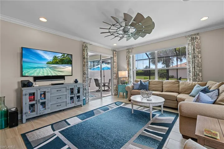 Living room featuring light wood-type flooring, ceiling fan, and crown molding