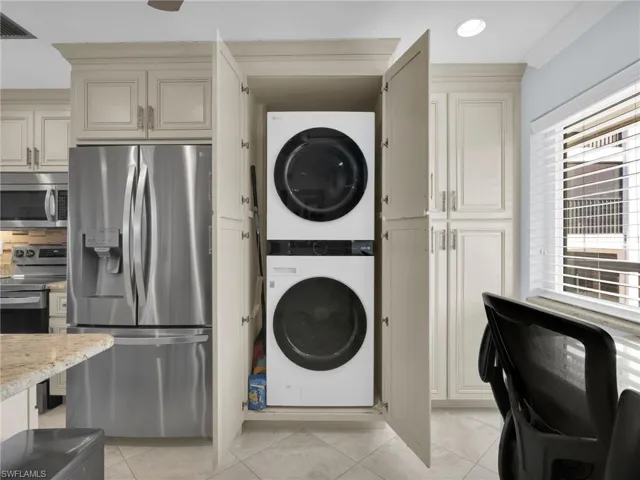 Laundry area featuring stacked washer / dryer and light tile patterned flooring