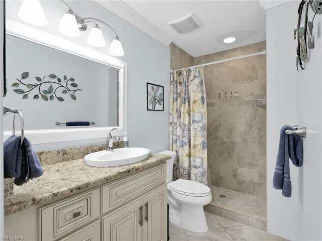 Bathroom with vanity, a stall shower, light tile patterned floors, and ornamental molding