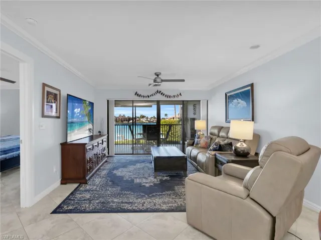 Living area with ceiling fan, crown molding, and light tile patterned floors
