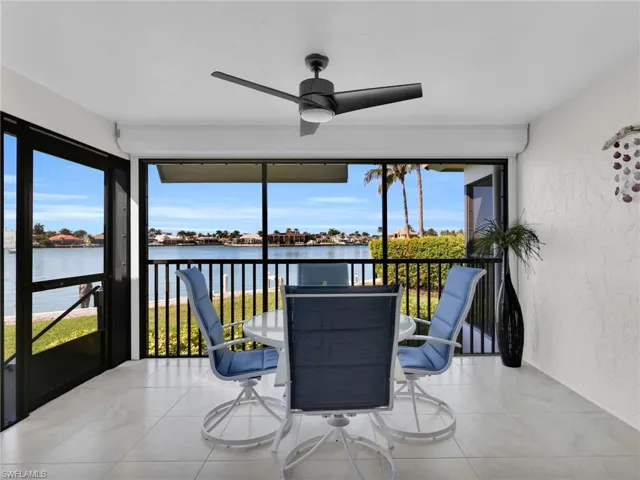 Sunroom / solarium featuring a textured wall, a water view, and tile patterned flooring