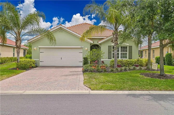 Single-story residence featuring a tile roof, light green stucco exterior, and a two-car garage