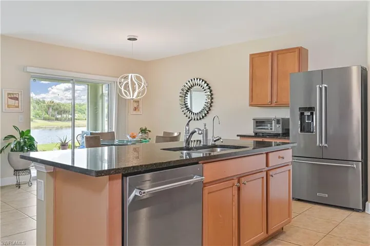 Kitchen featuring a central island with a built-in sink, dark speckled countertop, and stainless steel dishwasher