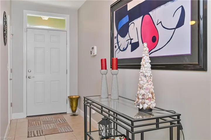Entryway featuring a white paneled door with transom window, light-toned tile flooring, and neutral wall paint
