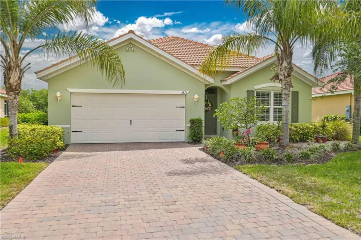 Single-story residence featuring a terracotta-tiled roof, light green exterior, and a paver driveway