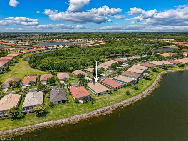 Waterfront property featuring a screened lanai and a manicured lawn