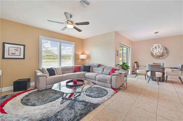 Open-concept living area featuring light-toned walls and tile flooring