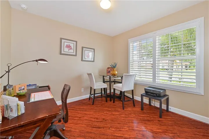Room featuring wood-finish flooring, neutral wall paint, and a large window with white plantation shutters