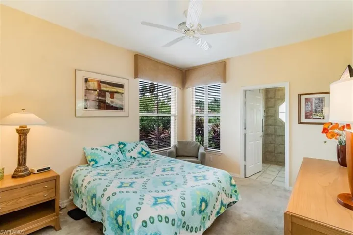 Bedroom with ensuite bathroom, ceiling fan, and carpet floors