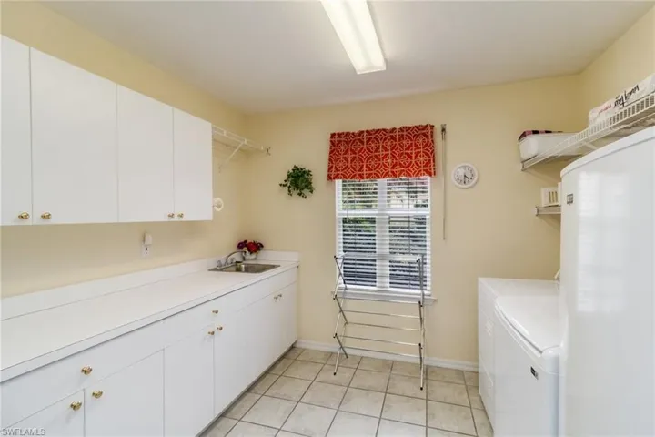 Laundry room featuring sink, washer and dryer, light tile flooring, and cabinets