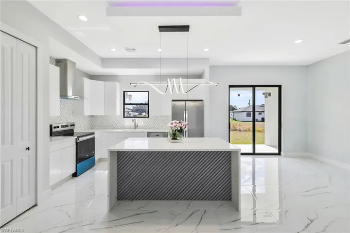 Kitchen with modern cabinets, white cabinets, decorative light fixtures, and stainless steel appliances