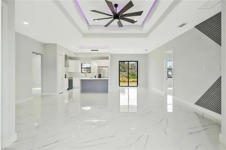 Unfurnished living room featuring a ceiling fan, recessed lighting, and a tray ceiling