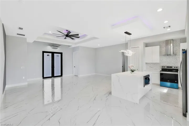 Kitchen featuring white cabinets, pendant lighting, stainless steel appliances, open floor plan, and a center island