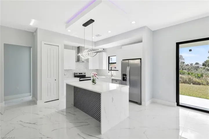 Kitchen featuring stainless steel appliances, pendant lighting, a center island, white cabinets, and modern cabinets