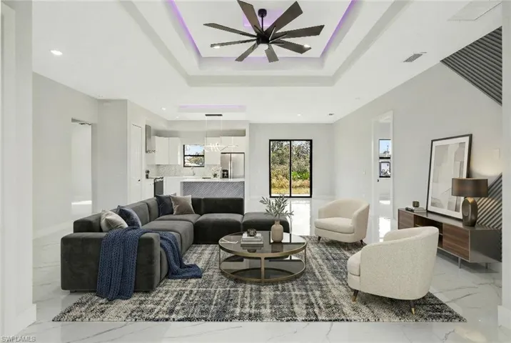 Living room with a ceiling fan, light marble finish floors, a raised ceiling, and recessed lighting