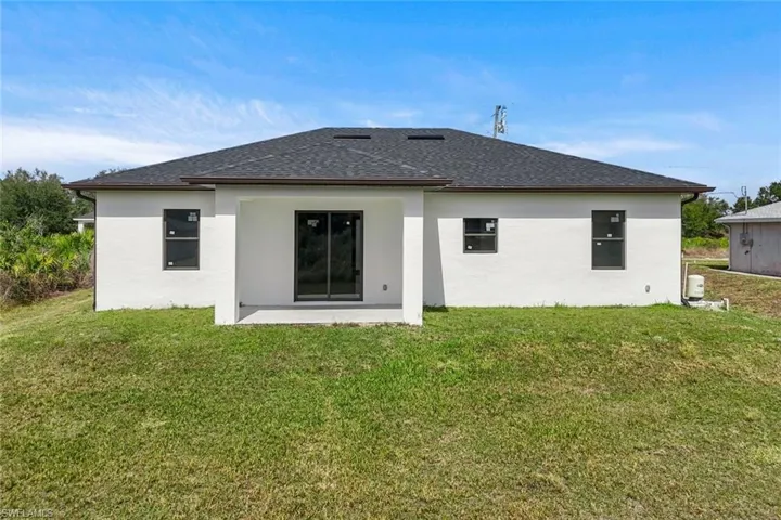 Back of house with stucco siding, a lawn, and a patio
