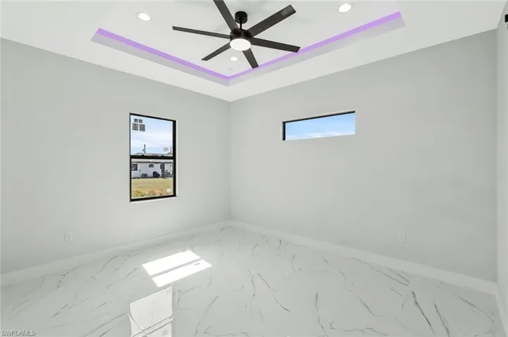 Empty room with marble look tiles, recessed lighting, a raised ceiling, and ceiling fan
