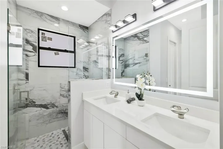 Bathroom with double vanity, a marble finish shower, and recessed lighting