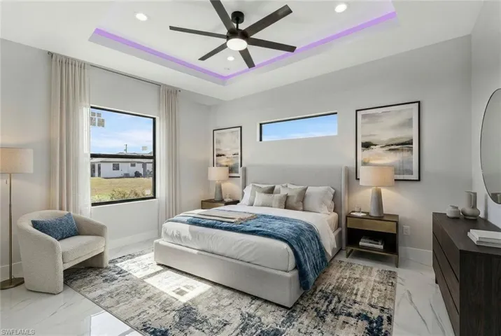 Bedroom featuring recessed lighting, multiple windows, ceiling fan, a tray ceiling, and light marble finish floors