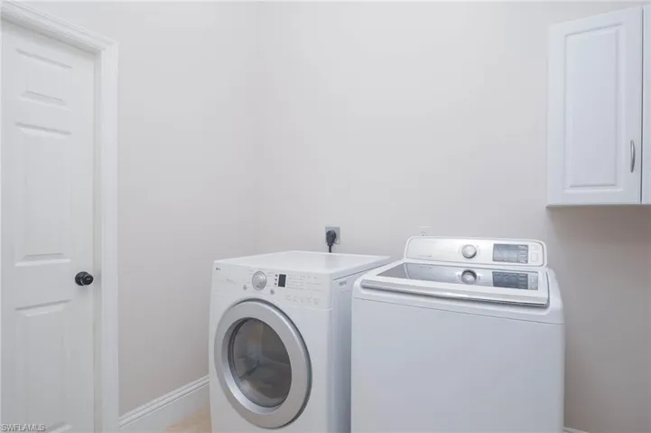 Washroom featuring separate washer and dryer and cabinets