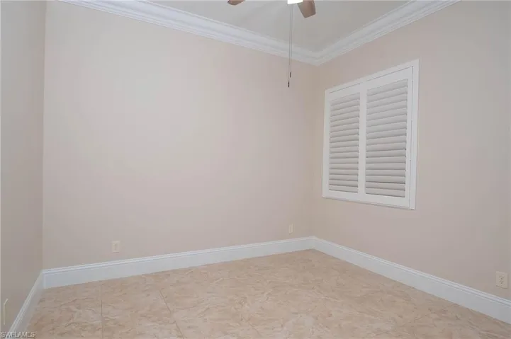 Spare room featuring ornamental molding, ceiling fan, and light tile patterned floors