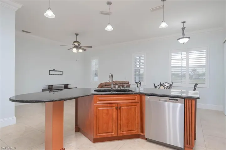 Kitchen with a center island, dishwasher, hanging light fixtures, sink, and ornamental molding