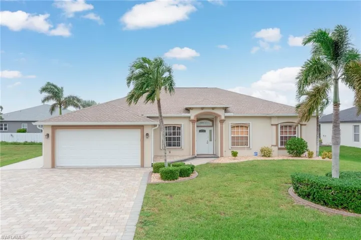 Single story home with a garage and a front lawn