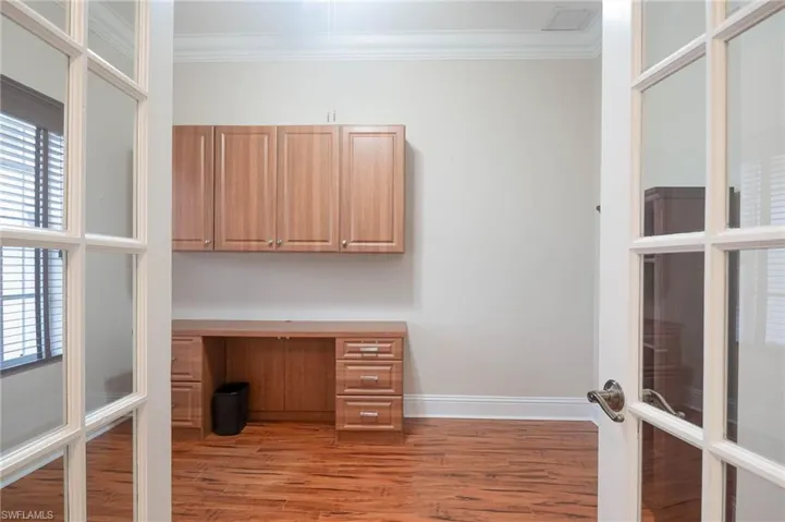 Unfurnished office with a wealth of natural light, ornamental molding, french doors, and hardwood / wood-style flooring