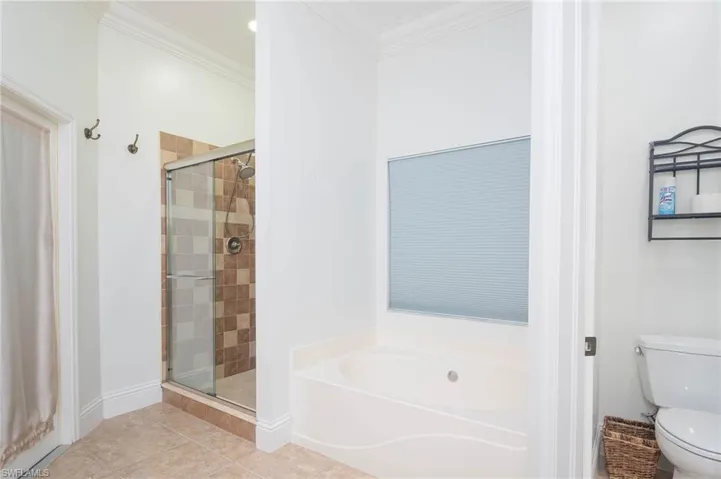 Bathroom with toilet, independent shower and bath, tile patterned floors, and ornamental molding