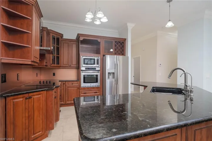 Kitchen with appliances with stainless steel finishes, sink, ornamental molding, and hanging light fixtures