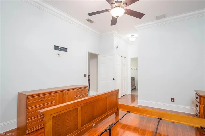 Bedroom featuring ceiling fan, a closet, light hardwood / wood-style flooring, and crown molding