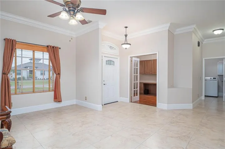 Unfurnished room with washer / dryer, ceiling fan, and crown molding
