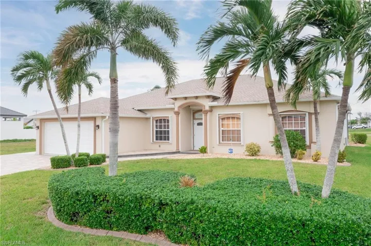 View of front of property featuring a garage and a front lawn