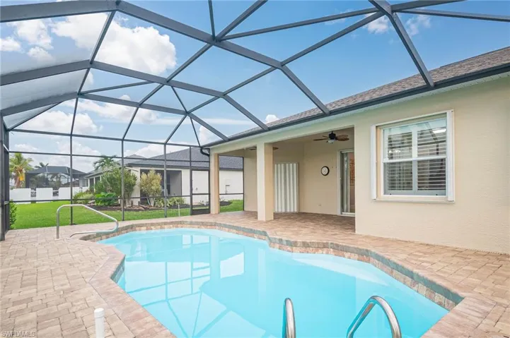 View of pool with glass enclosure and a patio area