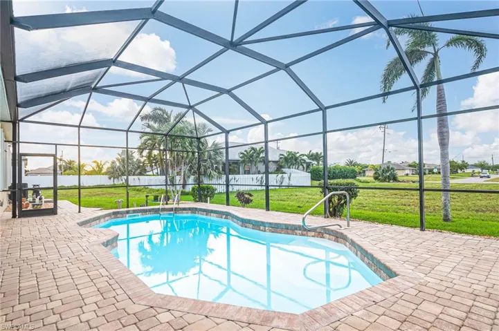 View of pool with a patio, glass enclosure, and a lawn