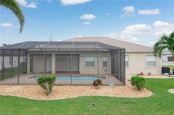 Rear view of property featuring a lanai, a patio, and a yard