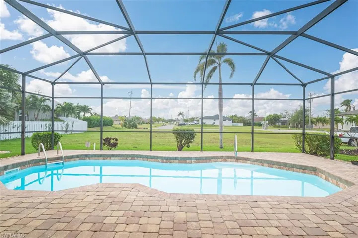 View of swimming pool with glass enclosure, a patio, and a yard